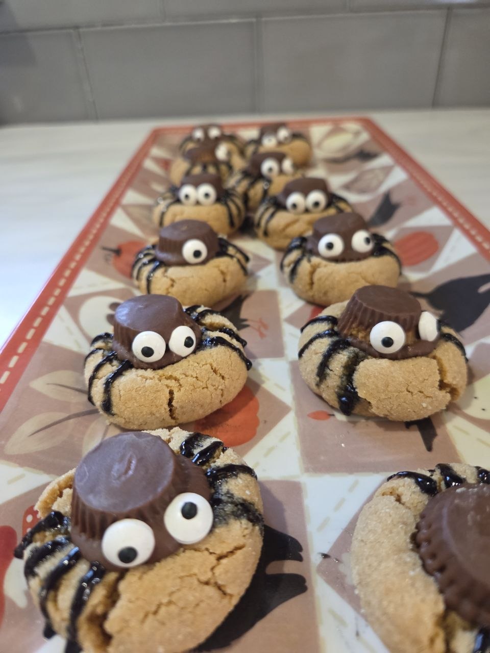 Peanut butter cookies topped with peanut butter cups, candy eyes and black icing legs to look like spiders
