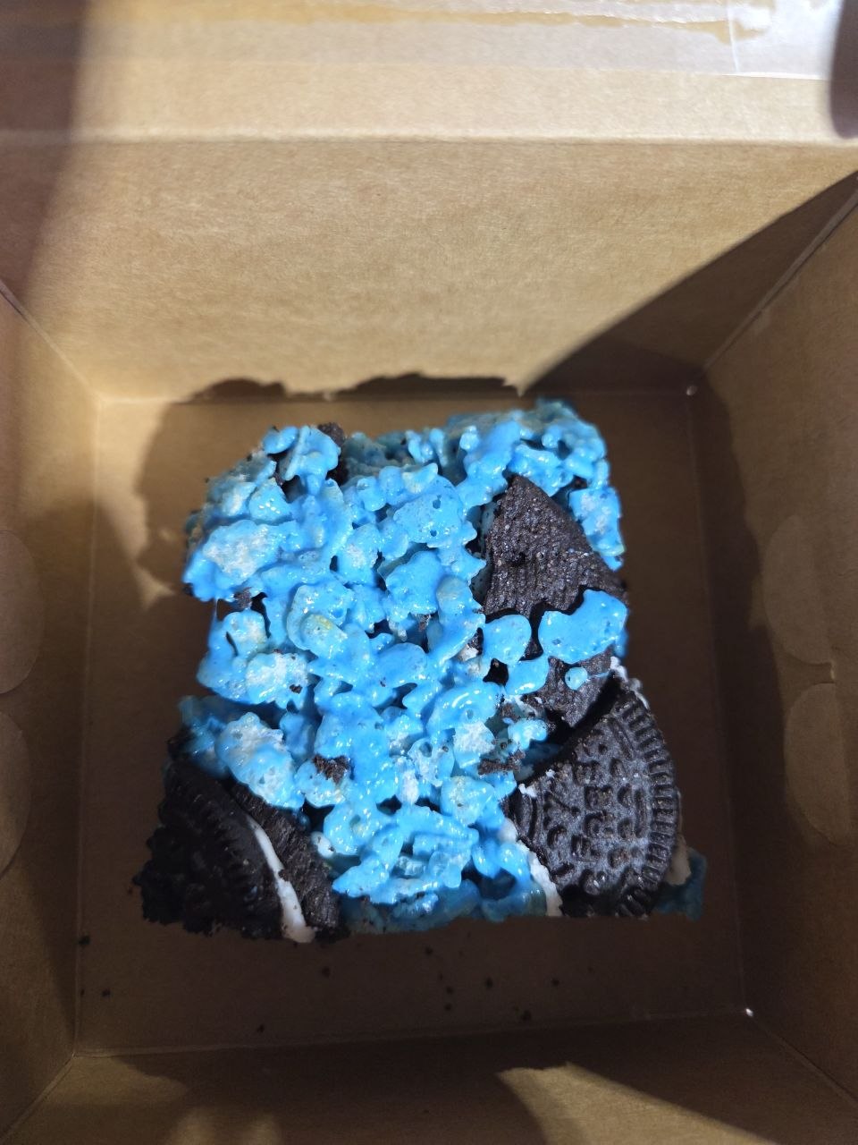 Blue Cookie Monster rice krispie treat with chunks of gluten-free Oreos in a kraft bakery box
