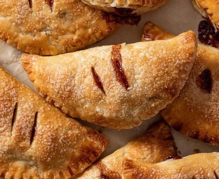 Golden apple hand pies with crimped edges and sugar-sprinkled tops